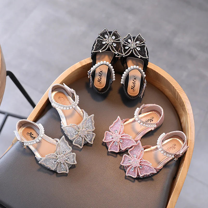 Summer girls' sandals with sequins, rhinestone bow, and flat heel. Available in sizes 21-35